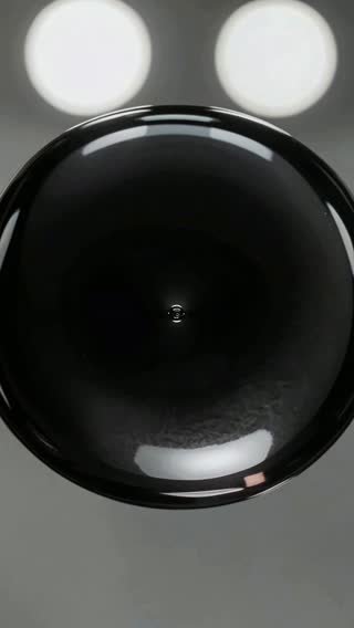 An extreme macro vertical close-up of a jet-black ferrofluid forming perfect, sharp geometric spikes as an…