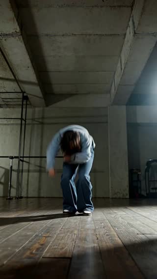 An energetic low-angle vertical shot of a model performing a contemporary dance move.